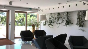 Ein modernes Interieur mit Glaswand, schwarzen Stühlen und einer Wandpflanze.