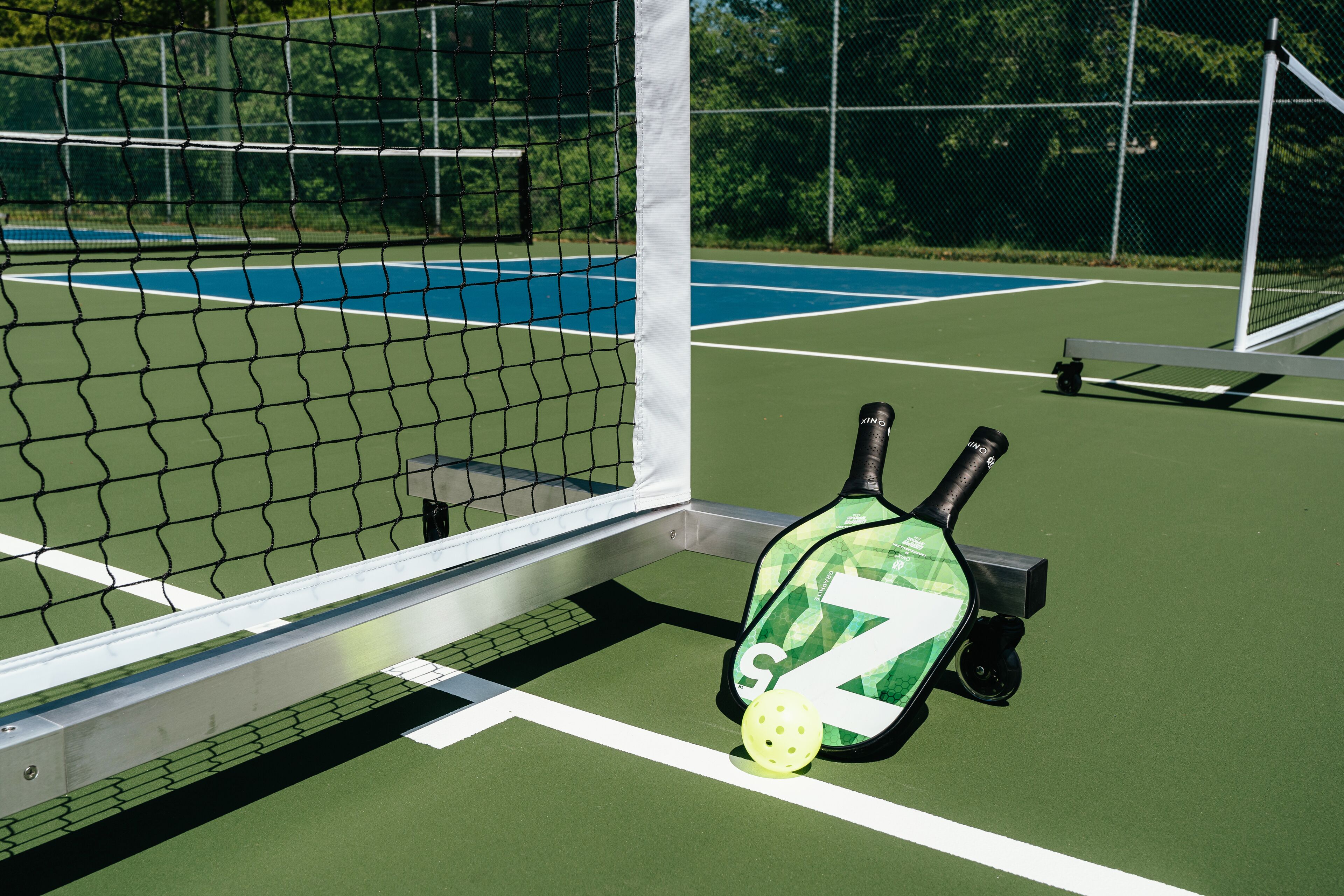 A tennis court with a net, a tennis racket, and a ball.