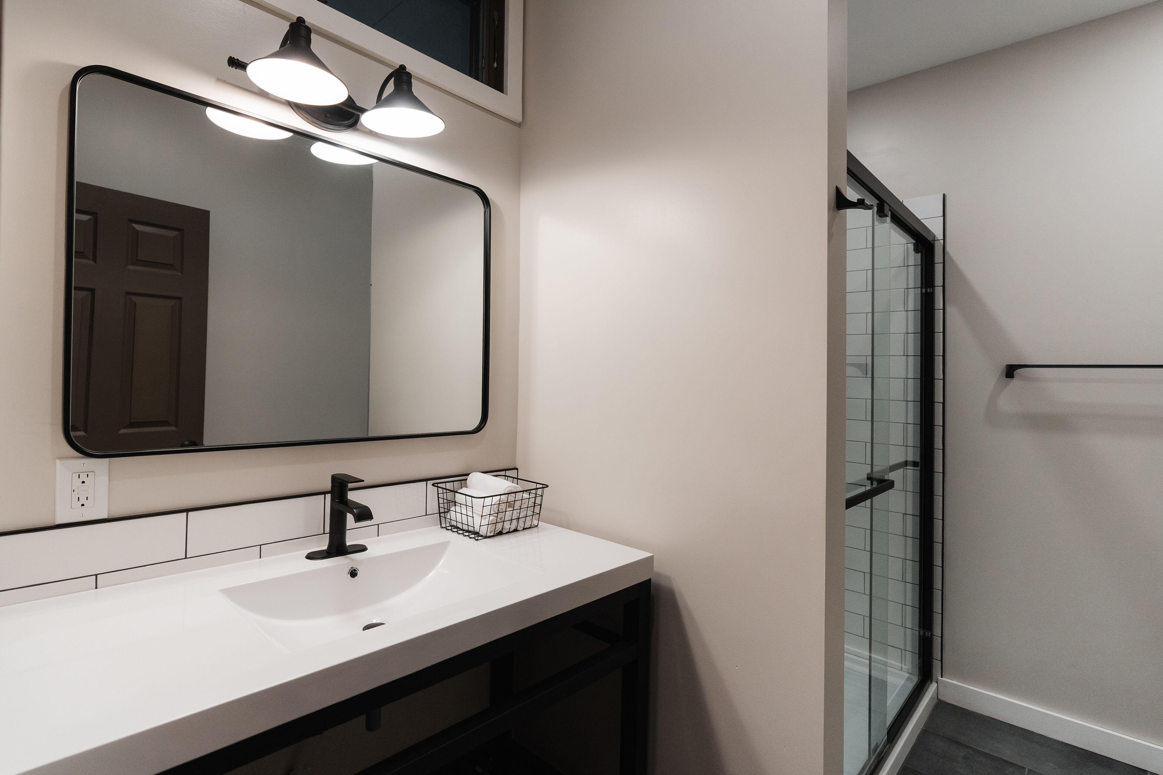 A bathroom with a white sink, a large mirror, and a glass shower enclosure.