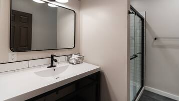 A bathroom with a white sink, a large mirror, and a glass shower enclosure.