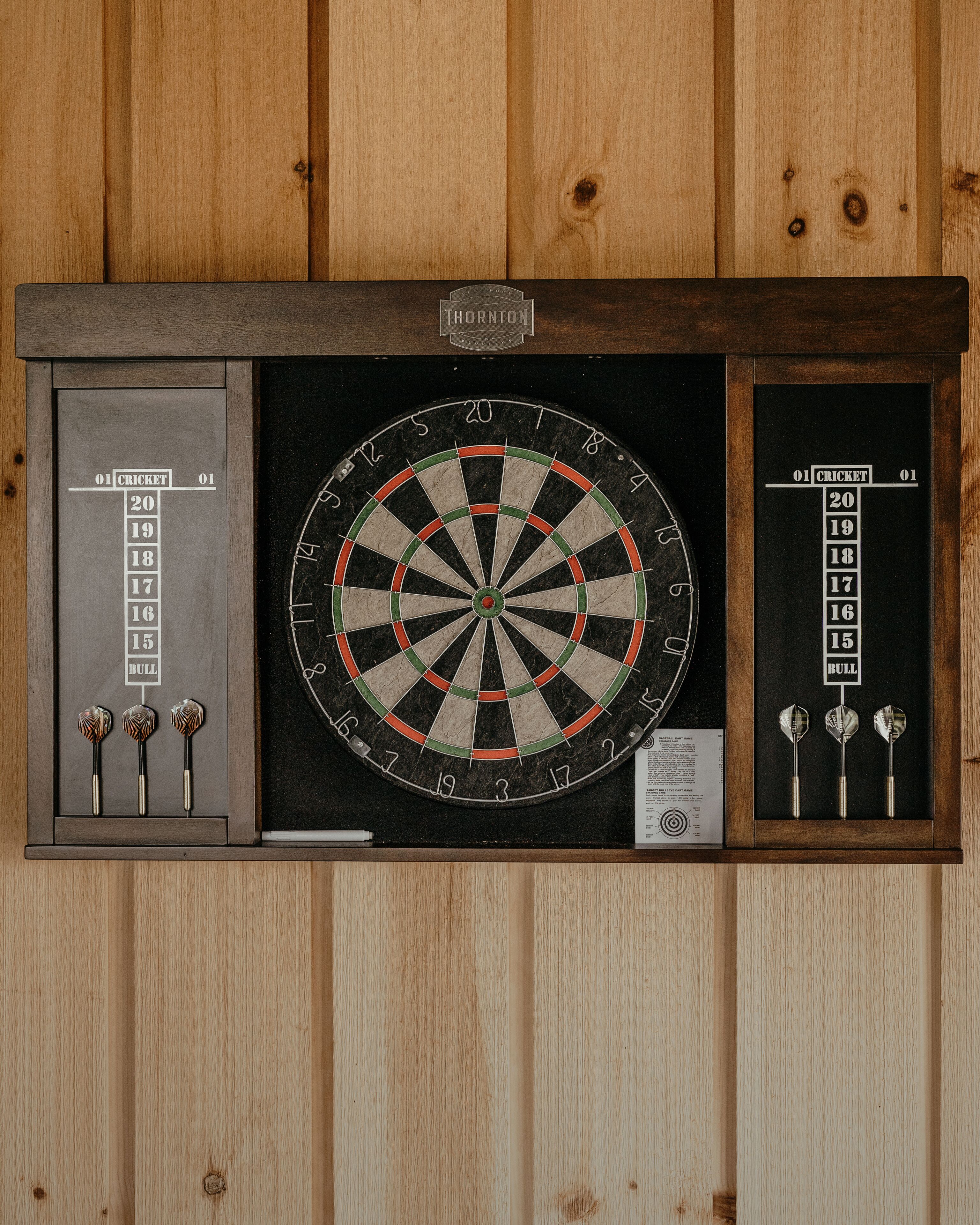 A dartboard mounted on a wooden wall with a dartboard cabinet below it.