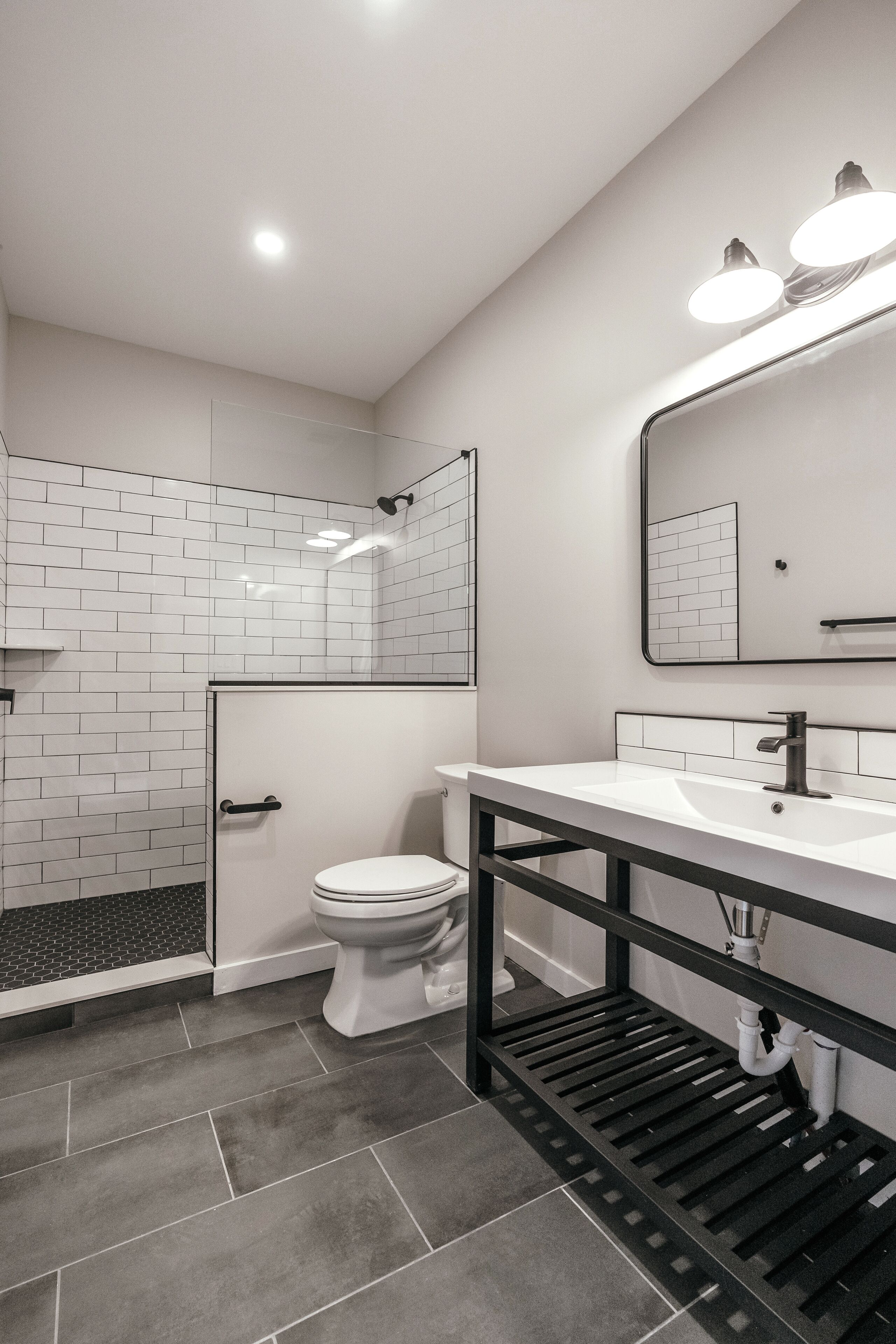 Een moderne badkamer met een douche, toilet en wastafel.