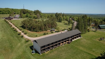 A large, modern building with a flat roof and multiple balconies, surrounded by well-maintained lawns and trees.