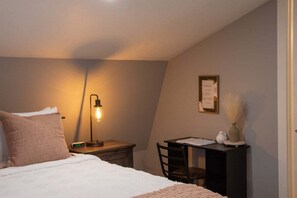 A bedroom with a bed, bedside table, lamp, chair, desk, and a framed note on the wall. - Amish Country Escape for Families & Friends (Warsaw)