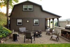 A two-story house with a patio area featuring outdoor furniture, a fire pit, and a grill. - Amish Country Escape for Families & Friends (Warsaw)