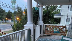Eine Veranda mit einem gemusterten Teppich, türkisfarbenen Stühlen und einem Blumentopf.