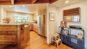Une cuisine spacieuse avec des meubles en bois, un réfrigérateur en acier inoxydable et un îlot central en bois.