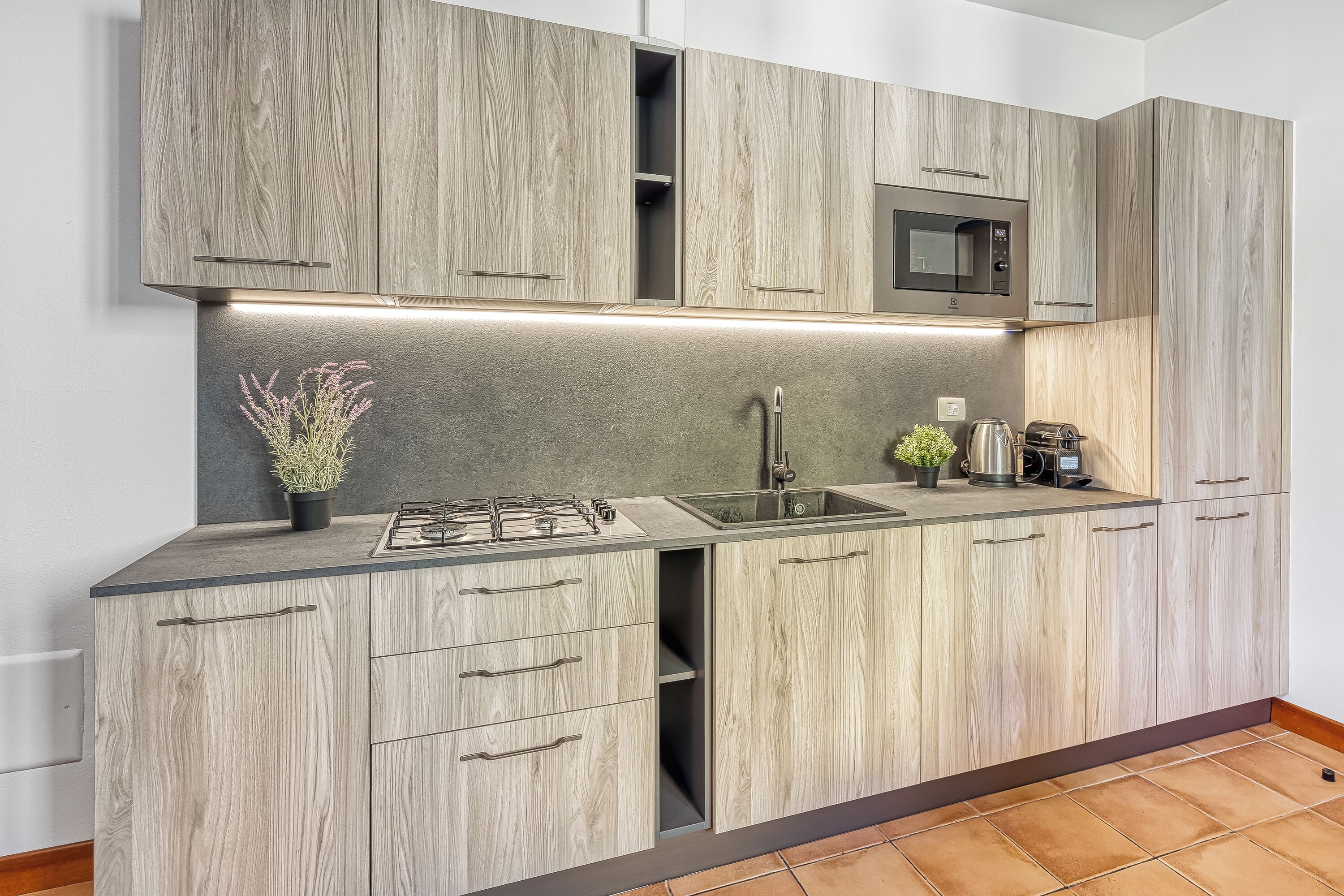 A kitchen with light wood cabinetry, a stainless steel range, a microwave, and a sink.