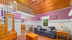 A spacious living room with a wooden staircase, a blue sofa, a wooden chest of drawers, and a patterned rug. - The Gables Wine Country Inn (Santa Rosa)