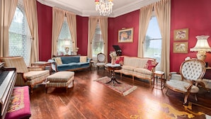 A spacious living room with a grand piano, plush seating, and a chandelier. - The Gables Wine Country Inn (Santa Rosa)