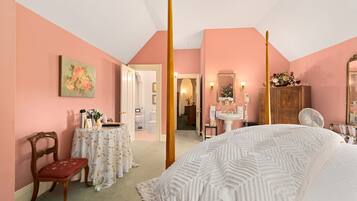 A bedroom with a four-poster bed, a vanity with a mirror, and a chair.