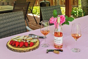 A table set with a bottle of wine, two glasses, a corkscrew, and a wooden board with strawberries and bread.