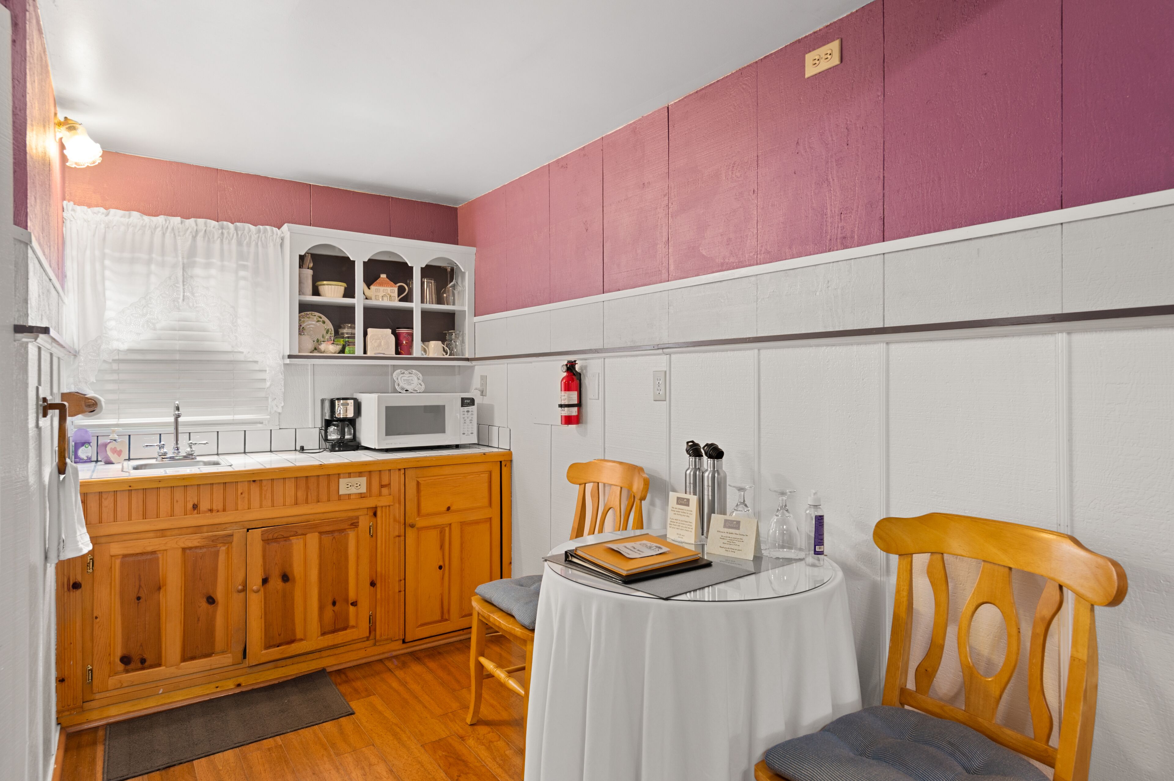 A compact kitchen with wooden cabinets, a microwave, and a small dining table with chairs.