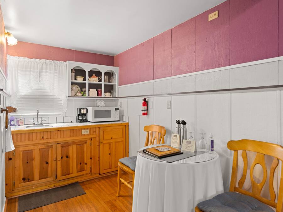 A compact kitchen with wooden cabinets, a microwave, and a small dining table with chairs.