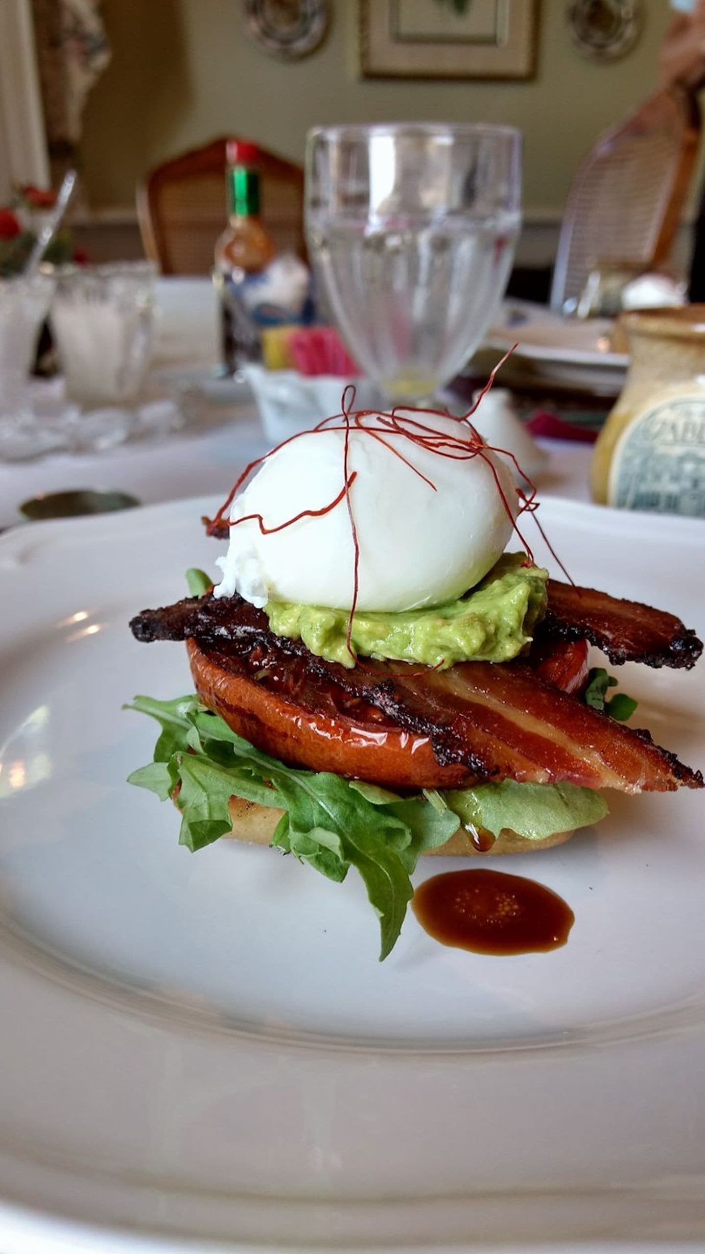 Une assiette avec un sandwich, de l’avocat, du bacon et un œuf poché.