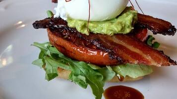 Une assiette avec un sandwich, de l’avocat, du bacon et un œuf poché.