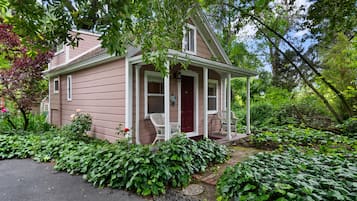 A single-story house with a porch, surrounded by lush greenery and a garden.