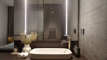 A modern bathroom with a large mirror, a white sink, and a shower area.