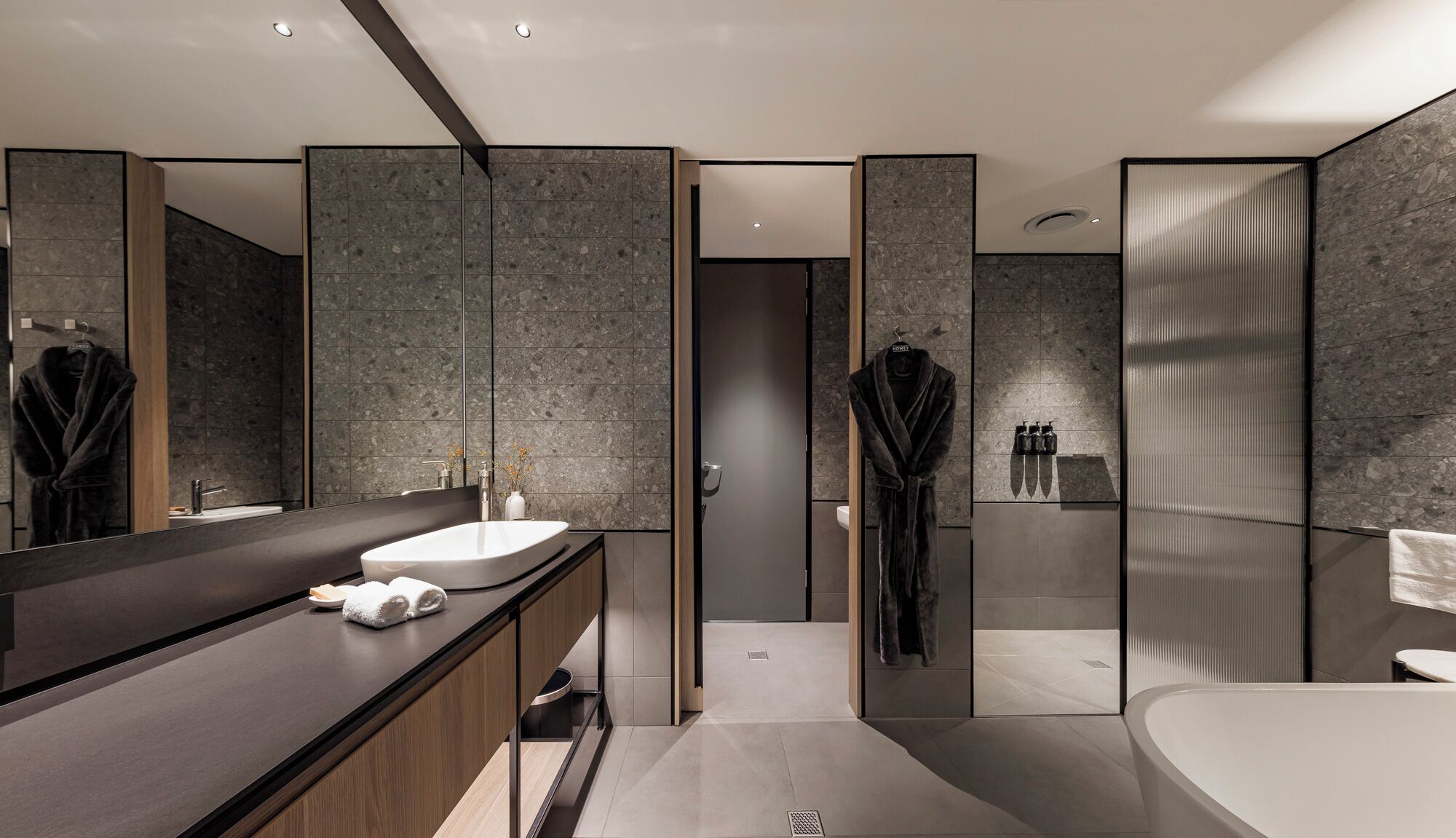 Ein modernes Badezimmer mit einem großen Spiegel, einer Badewanne und einem Waschtisch.