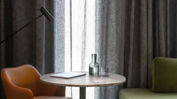 A room with a round table, a laptop, a bottle, and a glass.