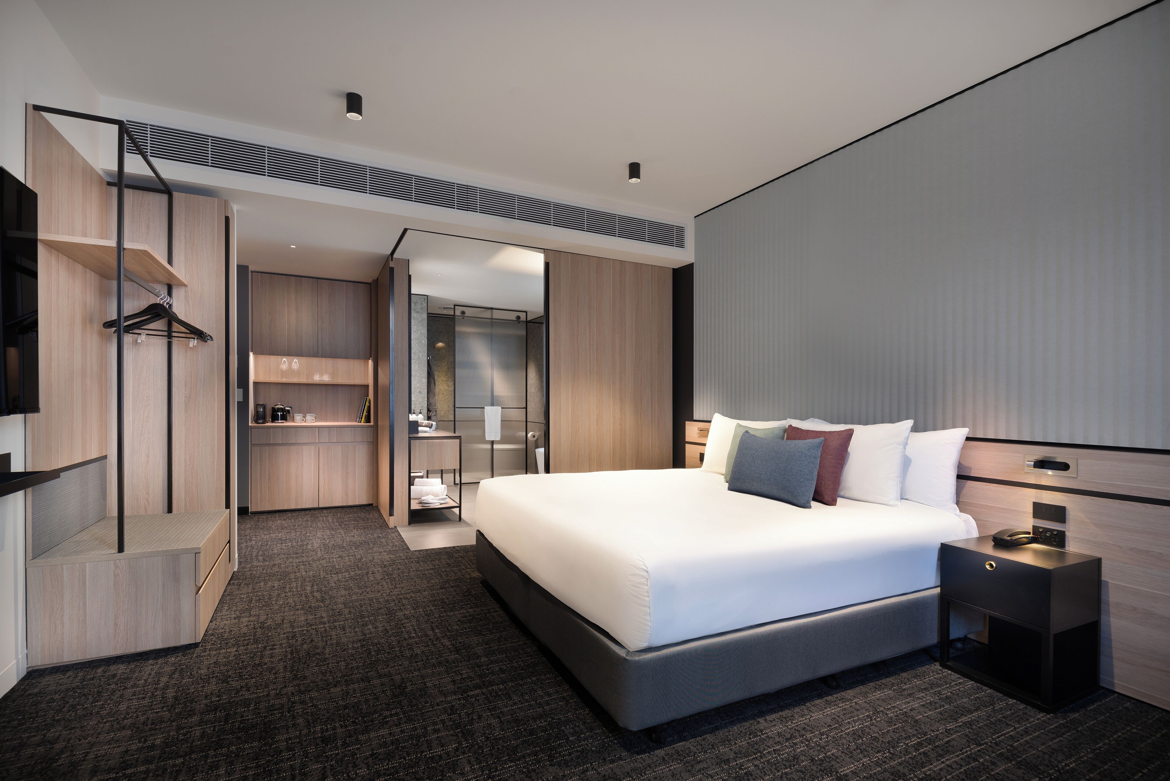 Een moderne hotelkamer met een groot bed, een inloopkast, een badkamer en uitzicht op de stad.