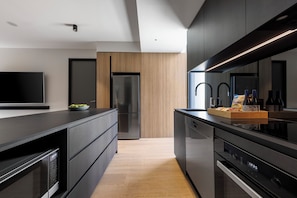 A modern kitchen with a built-in oven, a refrigerator, and a microwave.
