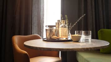A round table with a bottle of liquor, a bowl of cereal, and glasses.