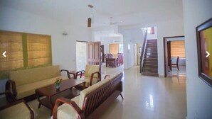 Amplia sala de estar con sofá, sillas, una mesa de comedor y una escalera que lleva a otro nivel.