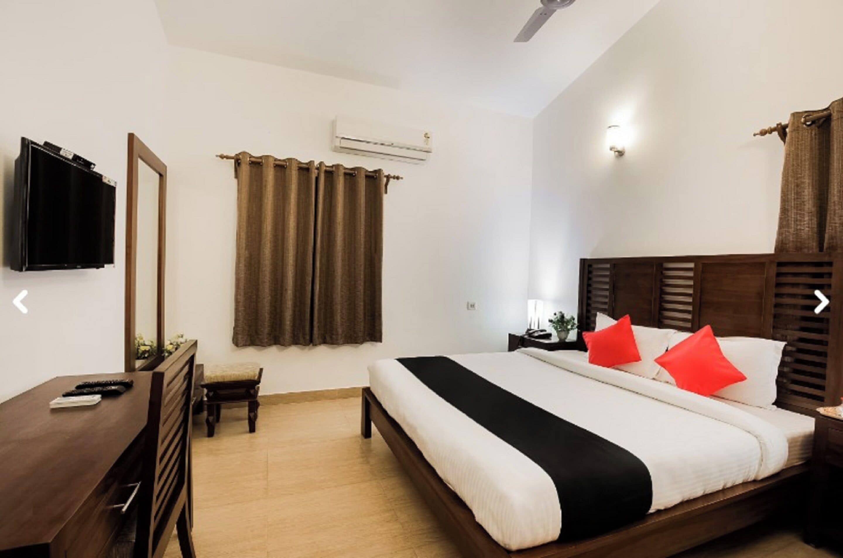 A bedroom with a bed, bedside table, and a desk with a chair.