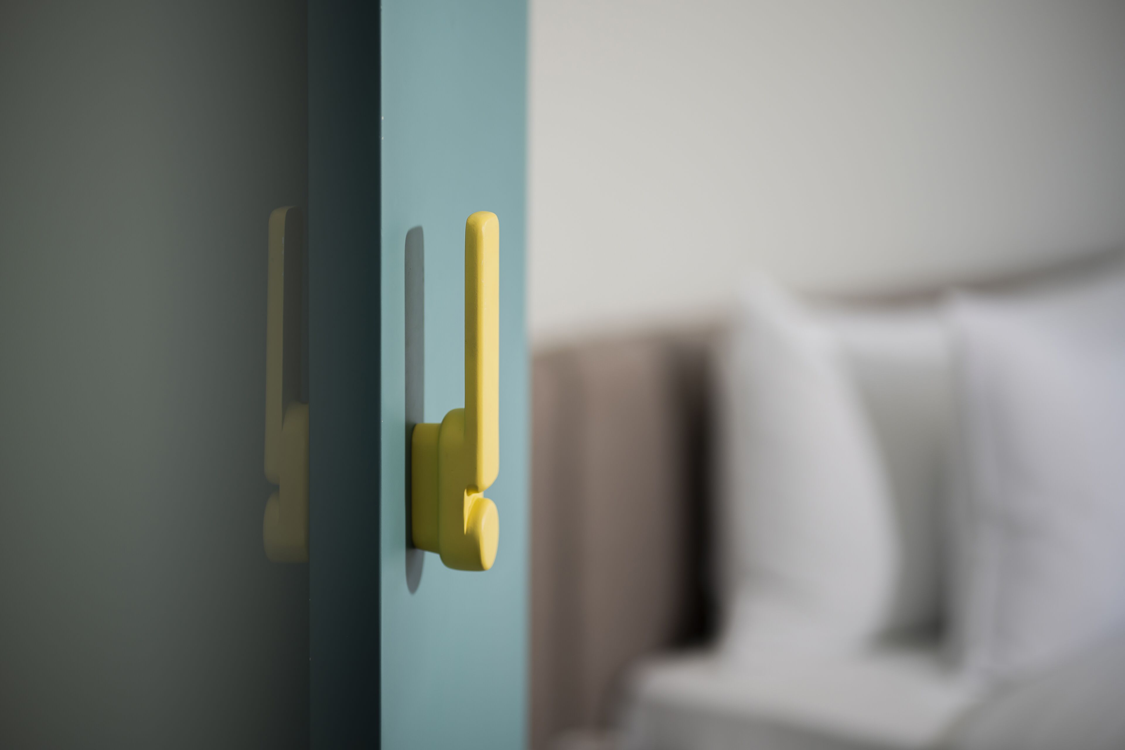 Primer plano de un pomo de puerta amarillo sobre una puerta verde azulada.