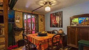 A dining area with a table set for four, wooden chairs, a chandelier, and a painting on the wall. - Ibirapuera Park House (São Paulo)