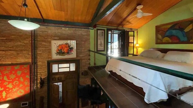 A room with a bed, wooden ceiling, and a painting on the wall. - Ibirapuera Park House (São Paulo)