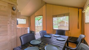 Une cabane en bois avec une table à manger dressée pour quatre personnes, des chaises et une fenêtre donnant sur une terrasse.