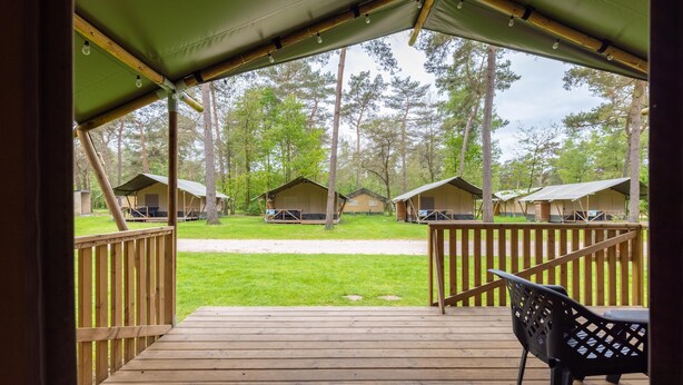 Une terrasse en bois offrant une vue sur plusieurs tentes installées dans un terrain de camping.