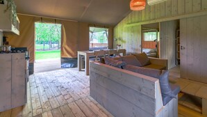 L’intérieur chaleureux d’un chalet comprend un coin repas en bois, un canapé et une cuisine équipée d’une cuisinière.