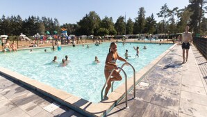 Une piscine avec des personnes dans l’eau et sur le bord.
