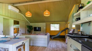 L’intérieur d’une cabane comprend un coin repas, une cuisine et un toboggan qui mène à une chambre à coucher située en mezzanine.