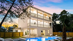 A two-story modern house with a swimming pool, outdoor seating, and a well-maintained garden.