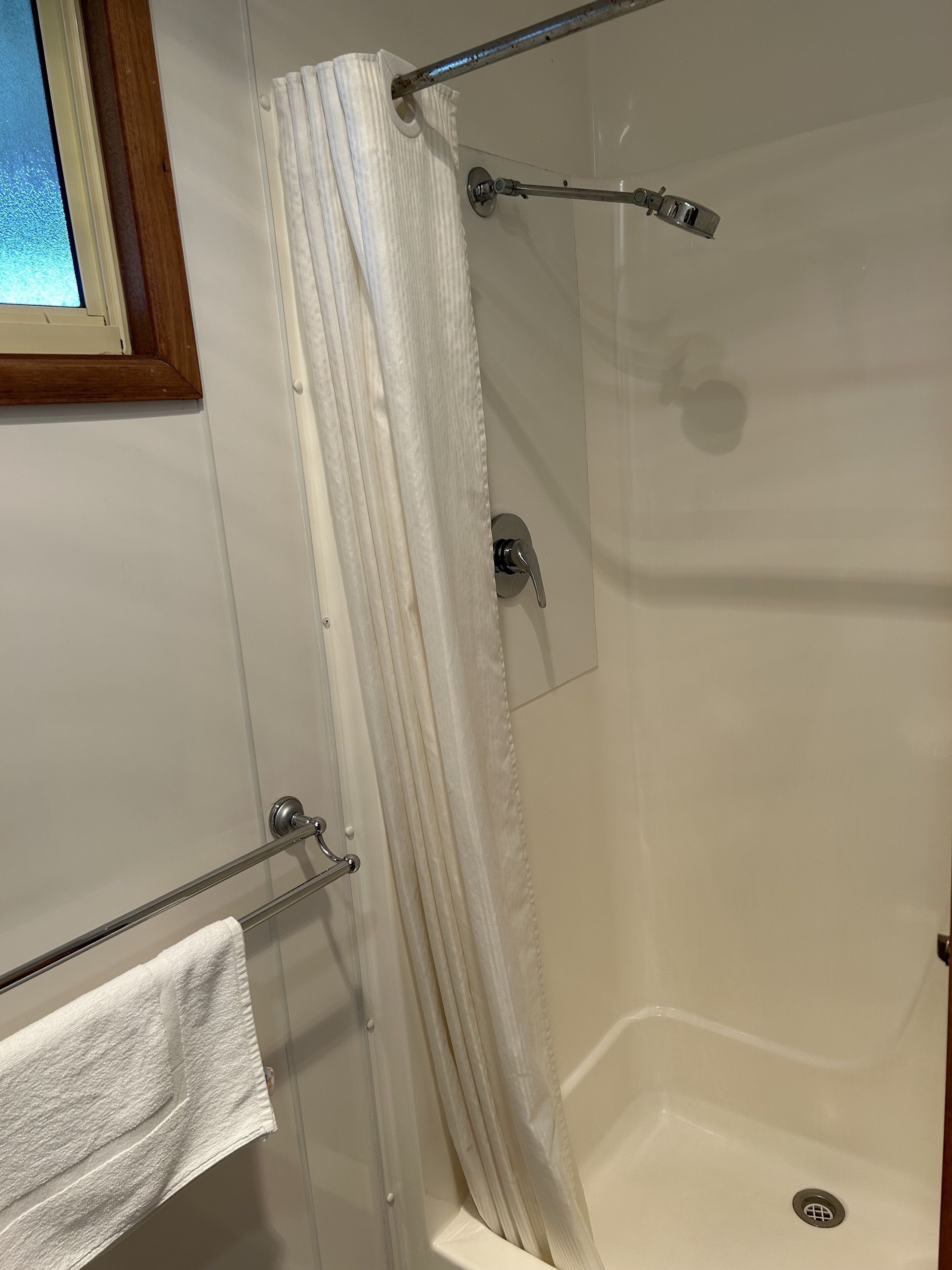 A shower with a glass door, a towel rack, and a curtain.