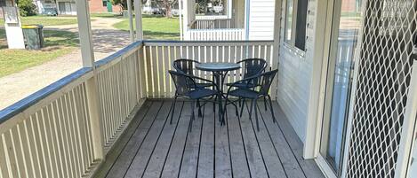 A wooden deck with a covered seating area, a metal grill, and a view of a residential area.
