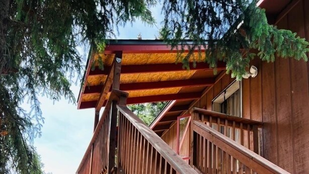 A wooden deck with a staircase leading to a covered area, a red mailbox, and a green tent in the background. - Cozy house close to all shops/malls, 7 minutes to fort wainwright  (Fairbanks)