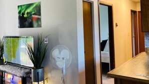 A modern living room with a flat-screen TV, a standing fan, and a bench. - Cozy house close to all shops/malls, 7 minutes to fort wainwright  (Fairbanks)