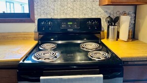 A black Frigidaire stove with four burners, a digital display, and a stainless steel hood. - Cozy house close to all shops/malls, 7 minutes to fort wainwright  (Fairbanks)