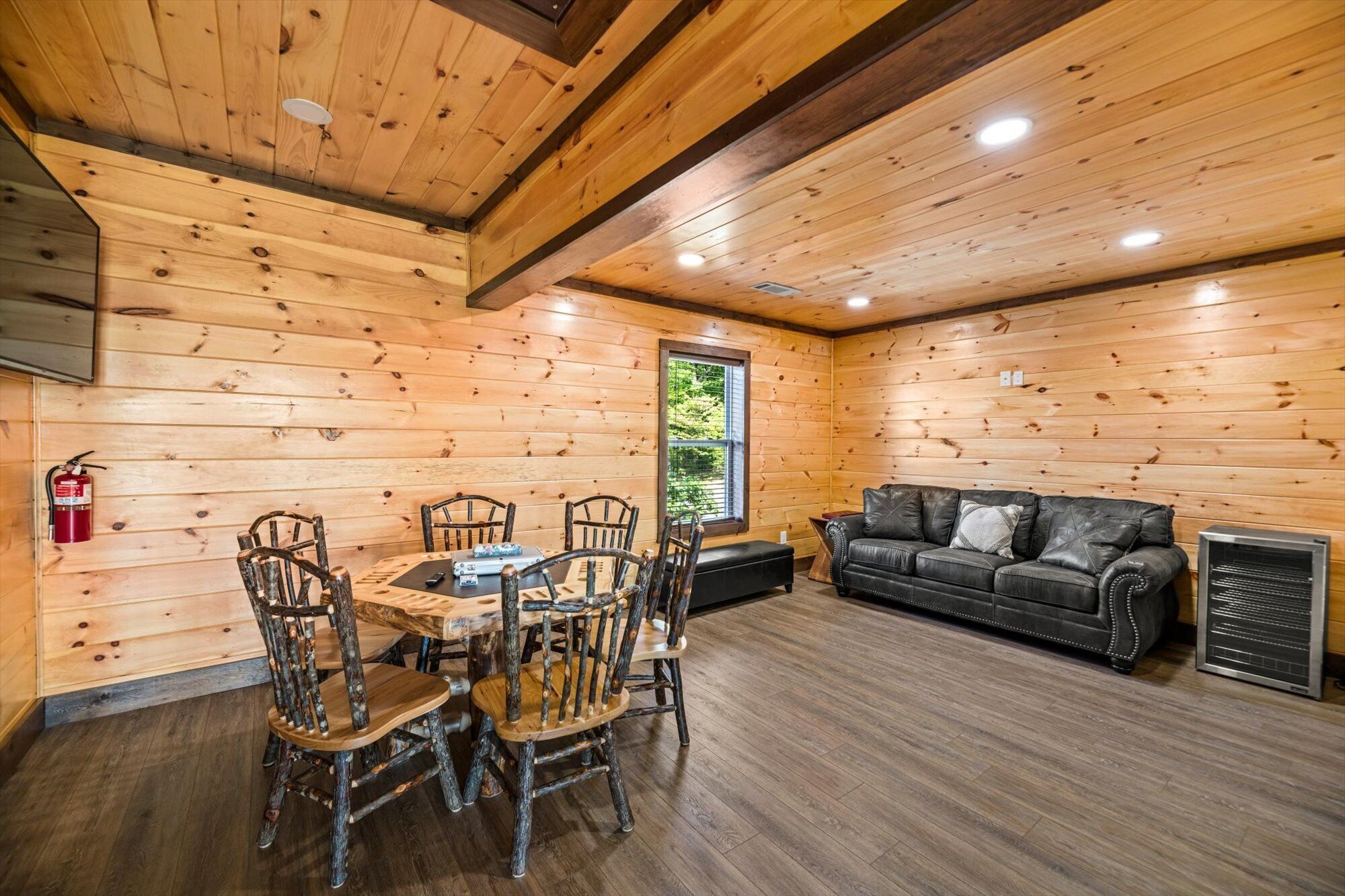 A cabin interior with a wooden interior, a dining table with chairs, a leather sofa, and a fireplace.