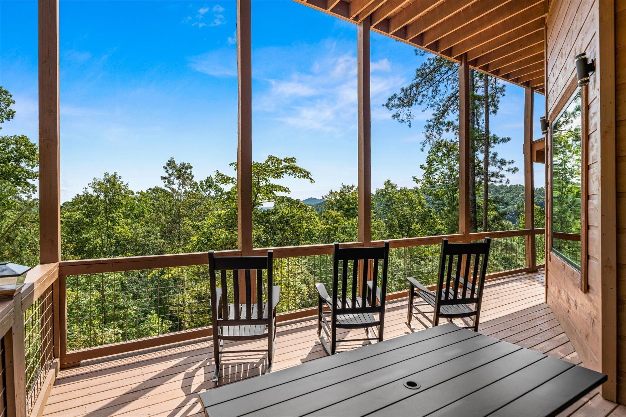 Une terrasse en bois avec une table et des chaises, donnant sur un paysage boisé.