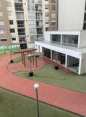 A modern building with a glass facade, outdoor seating area, and a brick pathway.