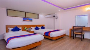 Una habitación de hotel con dos camas, un escritorio, una silla y un espejo.
