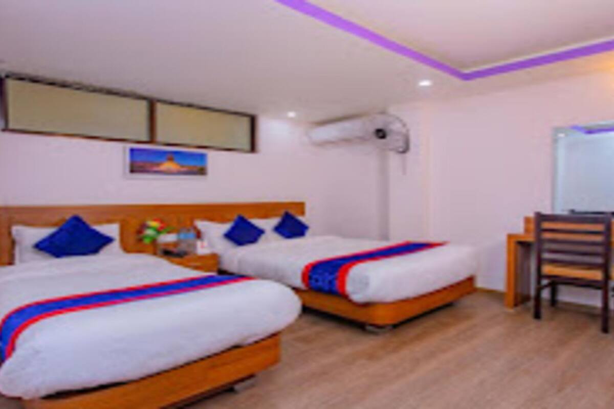 A hotel room with two beds, a desk, a chair, and a mirror.
