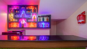 Una zona de bar con estantes llenos de botellas y un extintor en la pared.