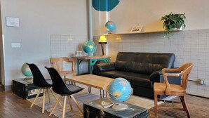 A cozy living area with a leather sofa, wooden chairs, a wooden coffee table, and a globe on a suitcase. - The Victor 2 - Cleveland's Urban Lodge (Cleveland)